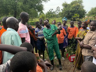 Robilert Ojobile, research manager, demonstrates tree planting with parents and students