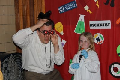 IGC Fellow posingn with young child in lab coat dressed like a scientist. 