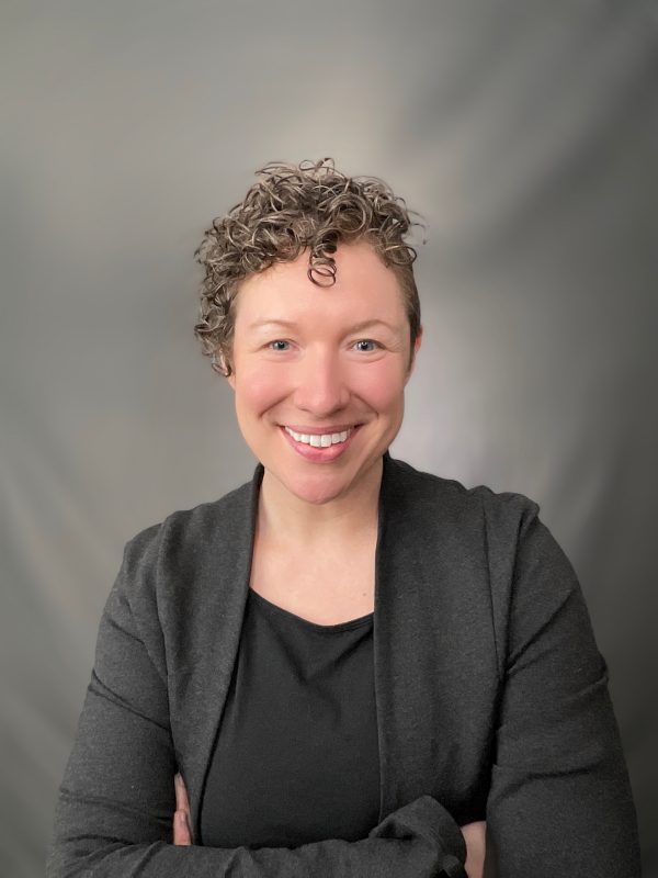 Laura Schoenle holding a red-winged blackbird in the field.
