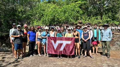 Faculty and students stand with Virginia Tech flag